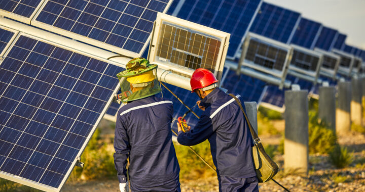 Asian engineer patrolling solar photovoltaic area under the setting sun